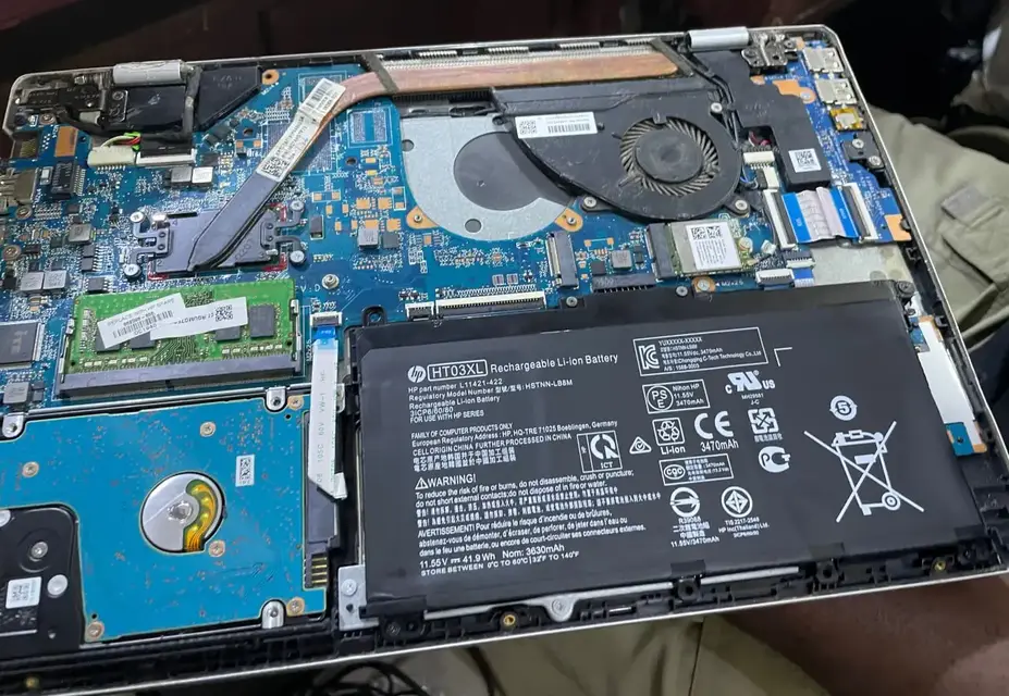 Inside of an HP laptop with the motherboard, fan and battery exposed