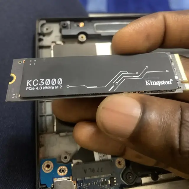 Kingston KC3000 NVMe SSD held above a laptop